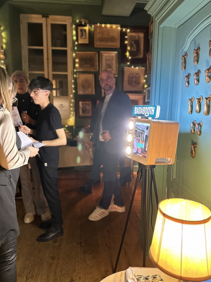 Des invités utilisent la borne photo dans une salle décorée de guirlandes lumineuses